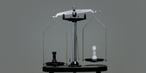 A black chess piece and a white chess piece stand on a modern scale