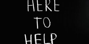 The words "HERE TO HELP" are emblazoned in chalk-like lettering on a black background.